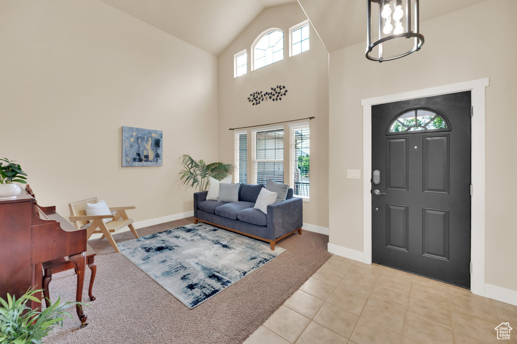 Tiled entryway with plenty of natural light, carpet flooring, a chandelier, and high vaulted ceiling
