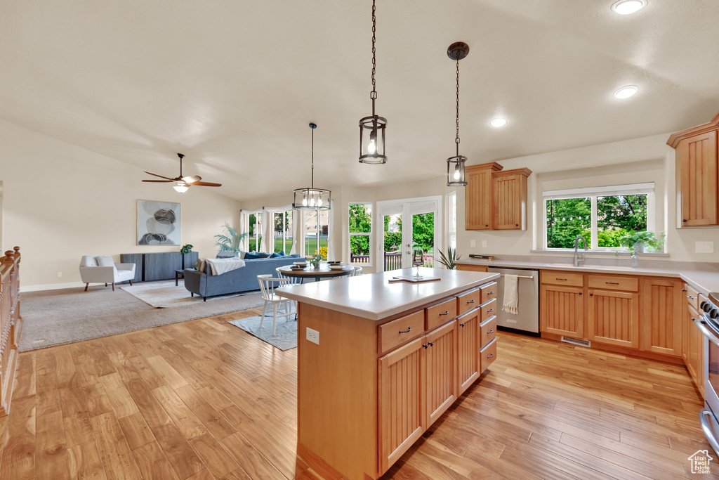 Kitchen with stainless steel appliances, open floor plan, light wood-type flooring, light countertops, and recessed lighting