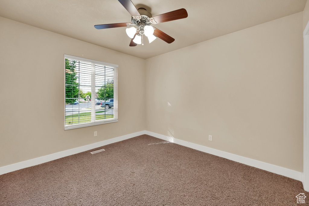 Empty room featuring dark carpet and a ceiling fan