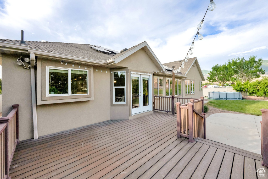 Wooden terrace with an outdoor pool, french doors, and a patio area