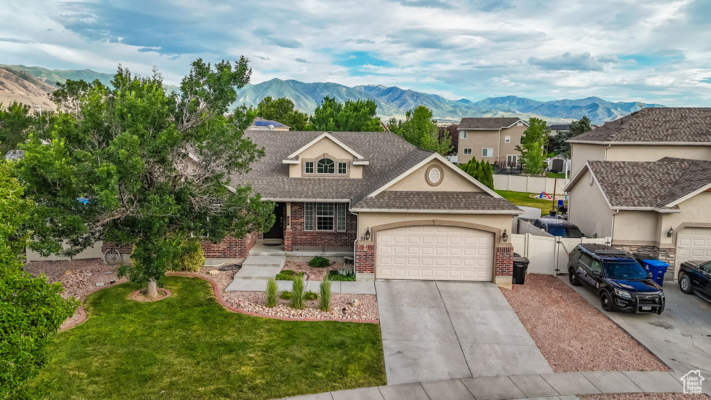 Traditional-style house featuring a shingled roof, a garage, brick siding, a mountain view, and concrete driveway