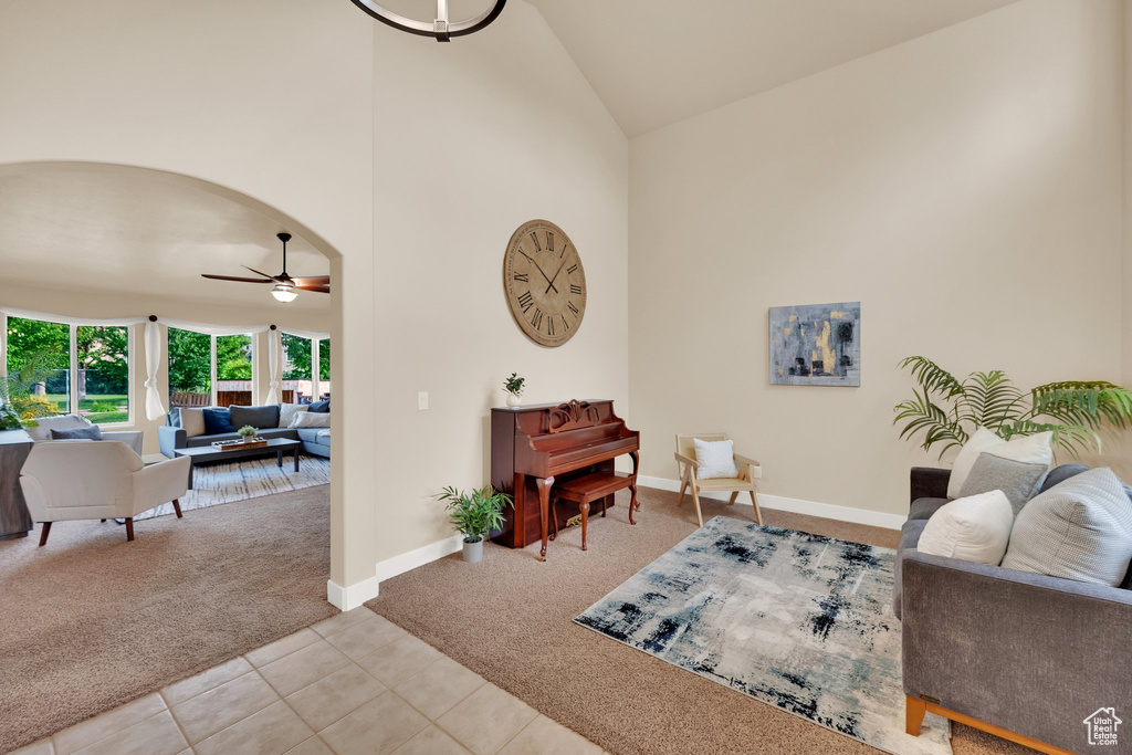 Tiled living area featuring carpet, high vaulted ceiling, ceiling fan, and arched walkways