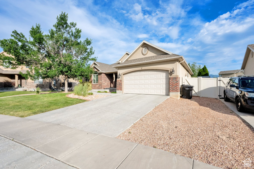 Ranch-style house featuring driveway, an attached garage, brick siding, and a gate