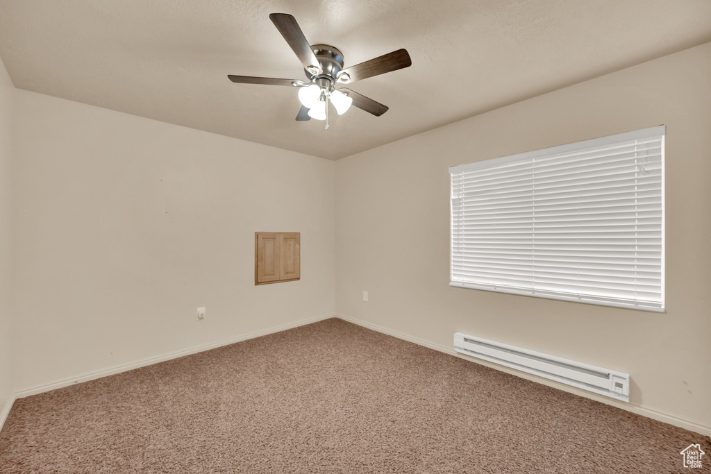 Carpeted spare room featuring a baseboard radiator and ceiling fan