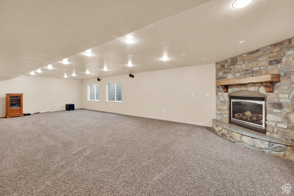 Unfurnished living room with a stone fireplace and carpet flooring
