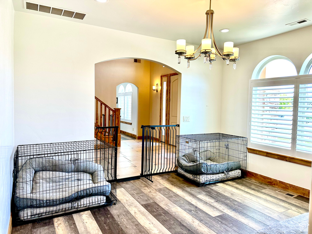Living area with arched walkways, wood finished floors, a chandelier, and recessed lighting
