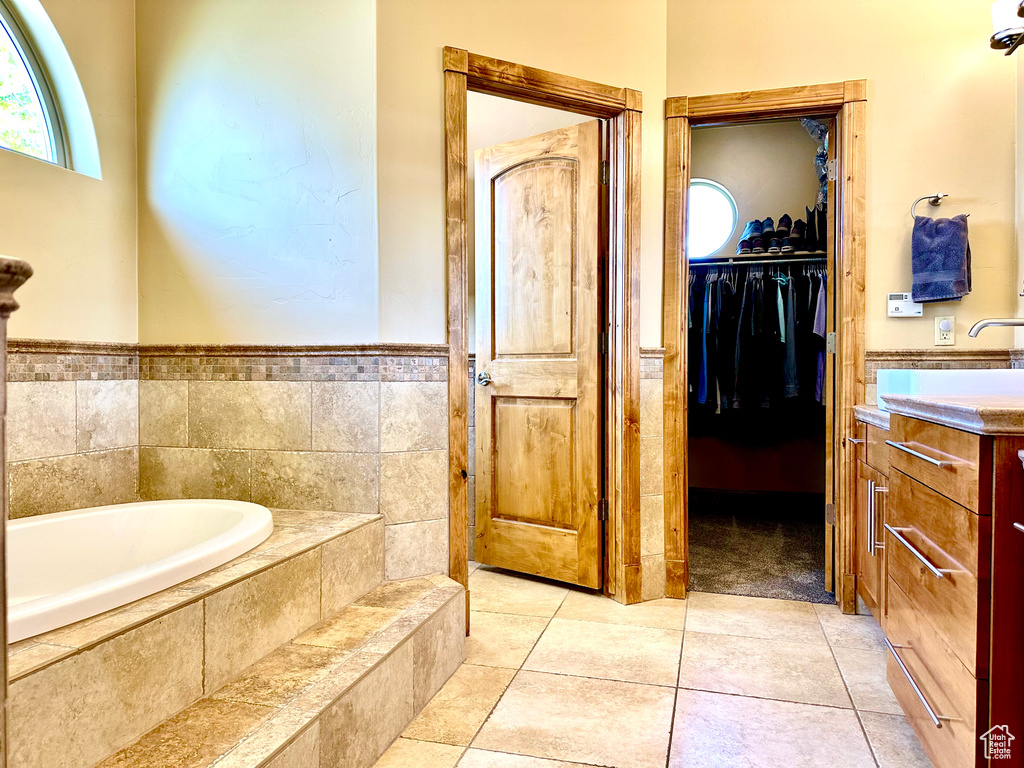 Full bathroom with a bath, vanity, a walk in closet, and tile patterned floors
