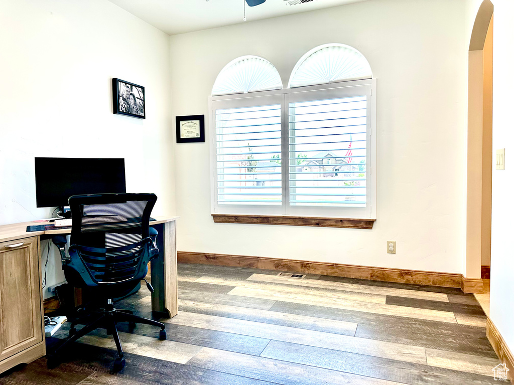 Office area with dark wood finished floors, arched walkways, and ceiling fan