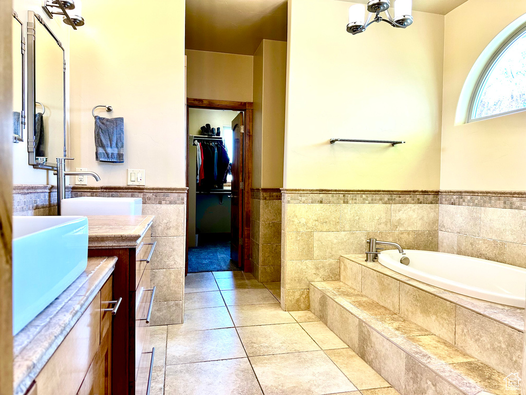 Full bath featuring vanity, a garden tub, a spacious closet, a wainscoted wall, and a chandelier