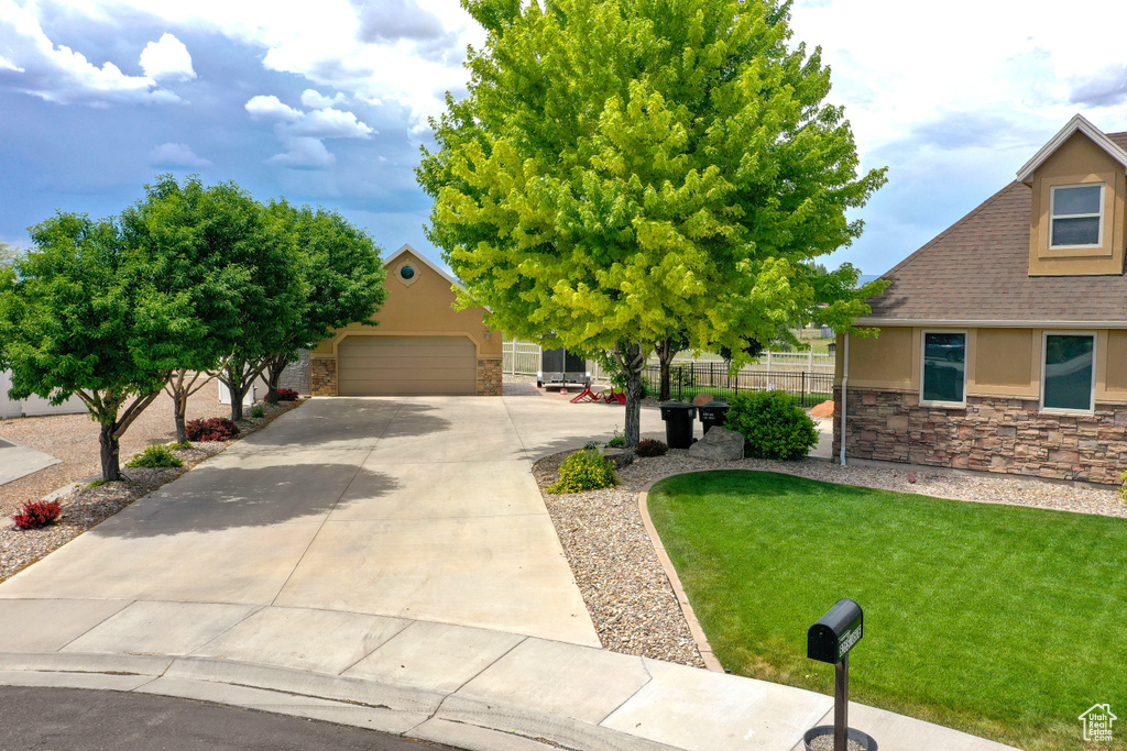 View of property hidden behind natural elements featuring stone siding, stucco siding, driveway, and a shingled roof