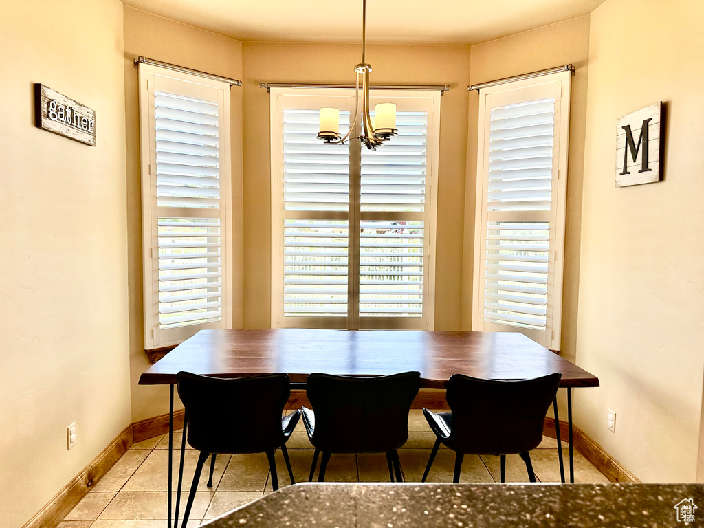 Tiled dining space featuring a chandelier and baseboards