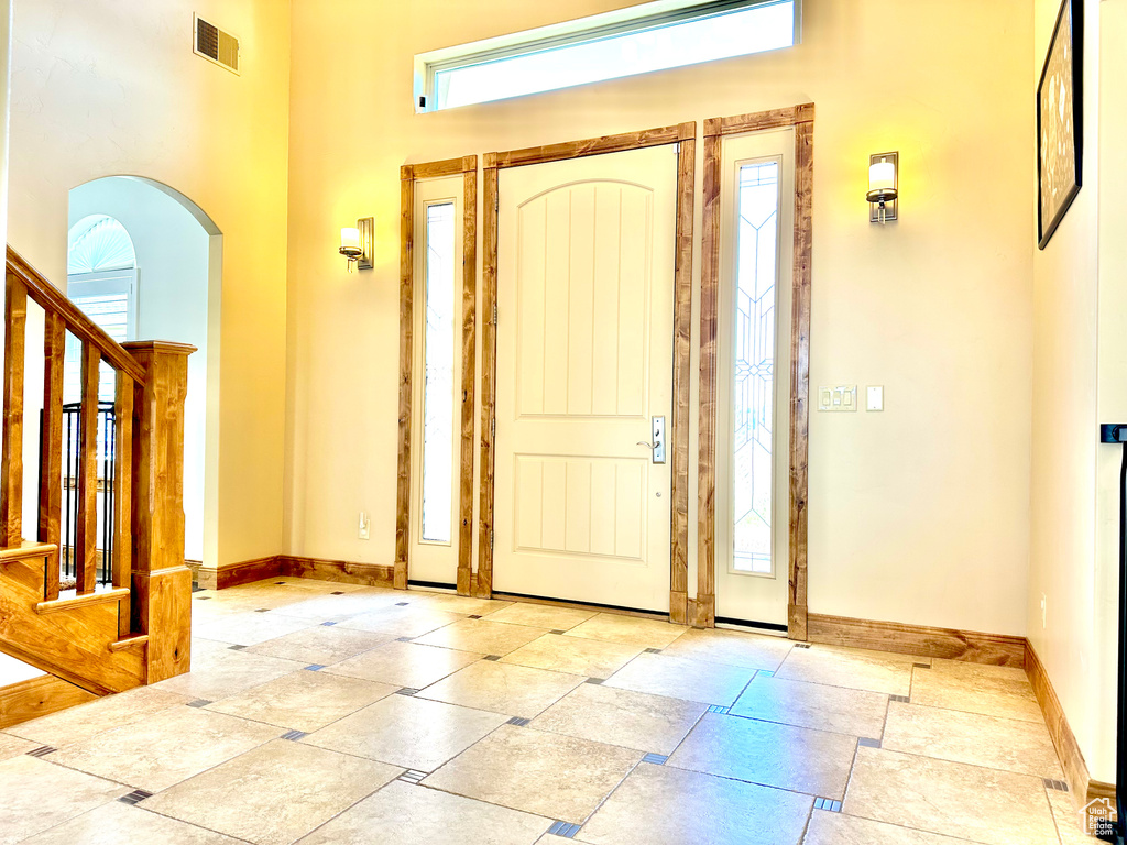 Foyer entrance featuring stairway, arched walkways, and a high ceiling