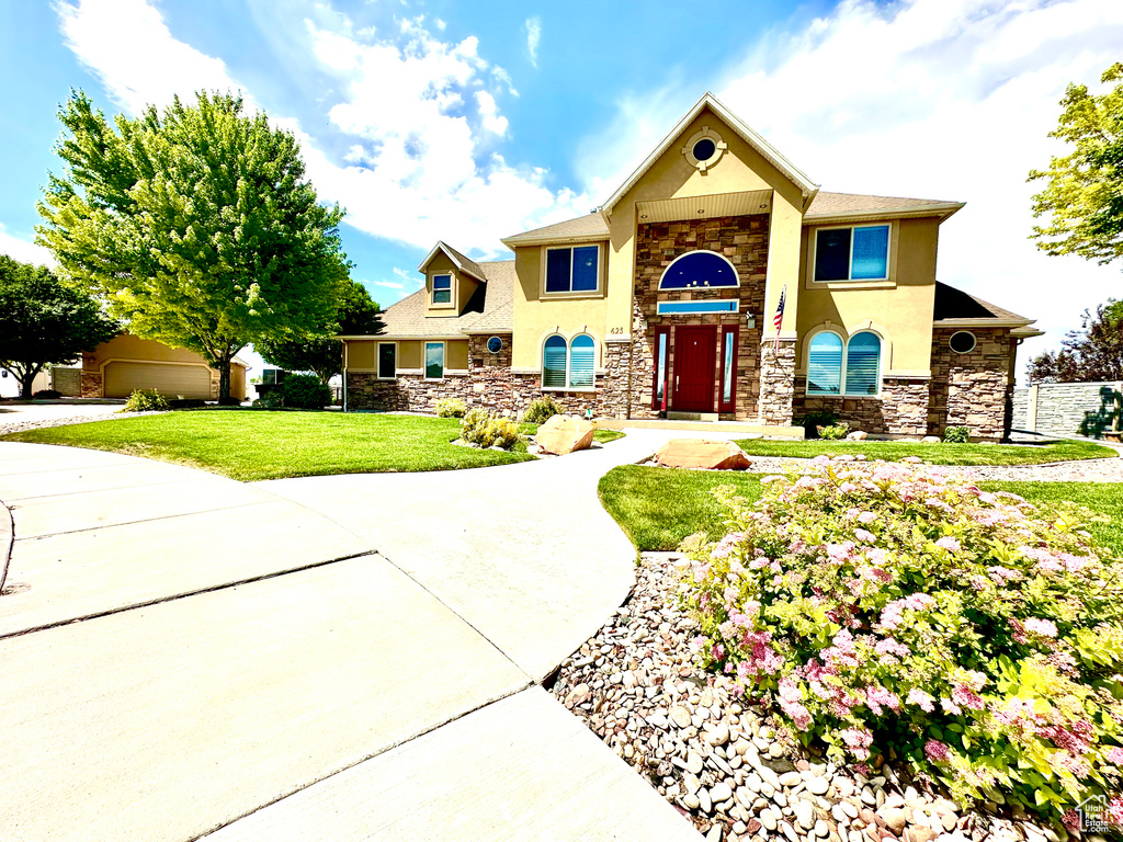 View of front facade with stone siding, stucco siding, and a front lawn
