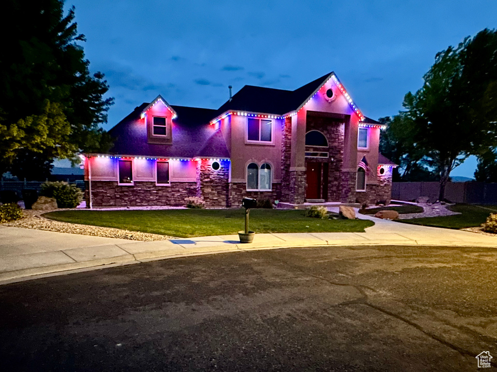 View of front of property featuring stone siding, a front lawn, and stucco siding