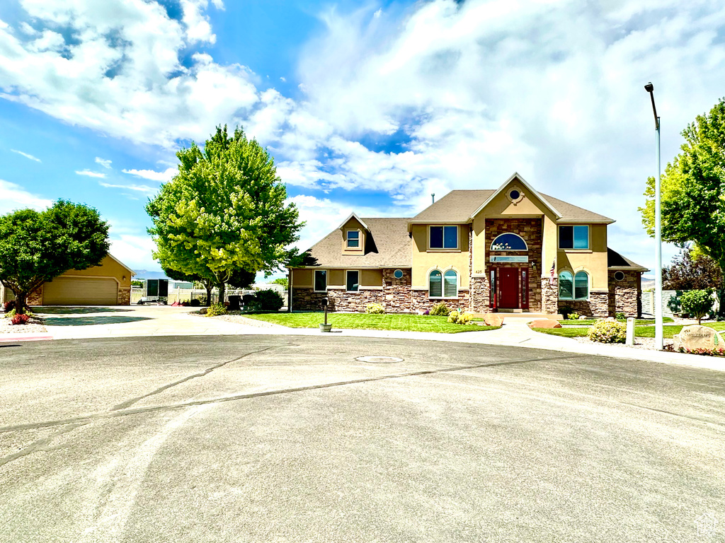 View of front facade featuring stone siding, stucco siding, and concrete driveway