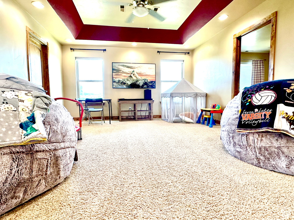 Bedroom with multiple windows, a tray ceiling, and carpet