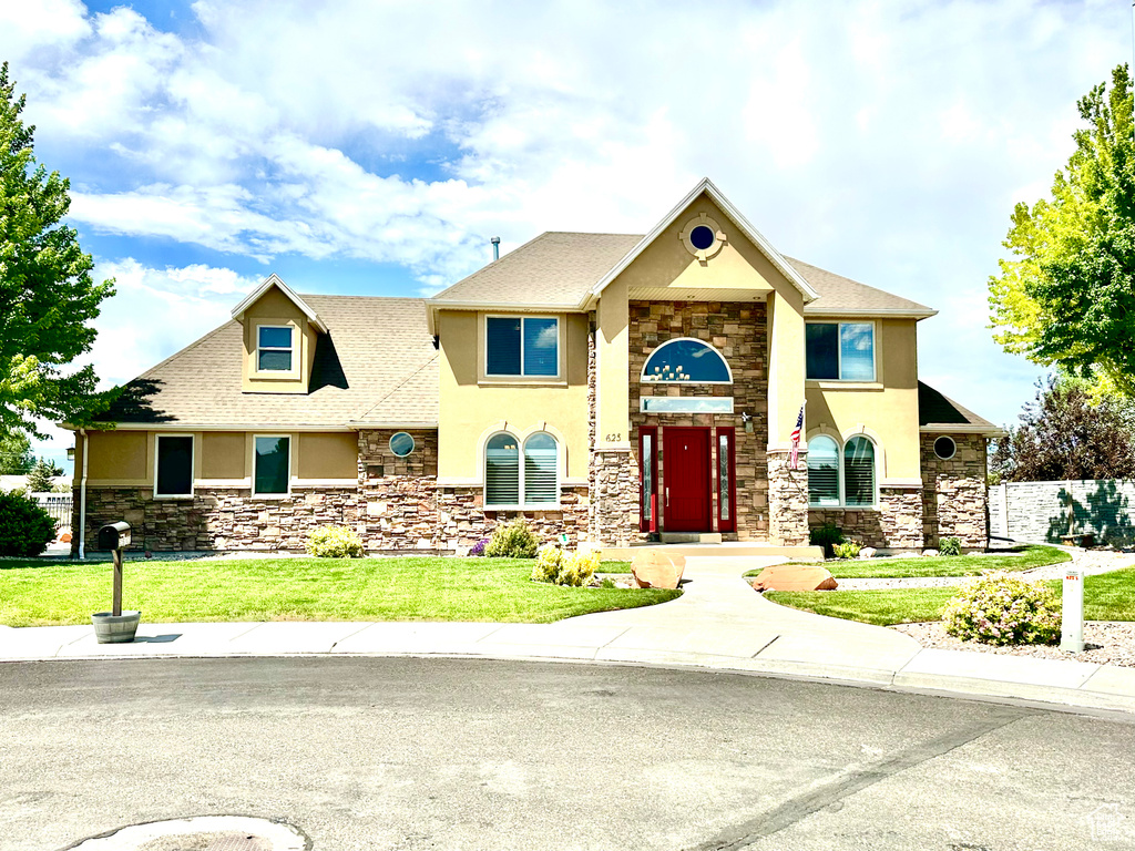 View of front facade featuring stone siding, stucco siding, and roof with shingles