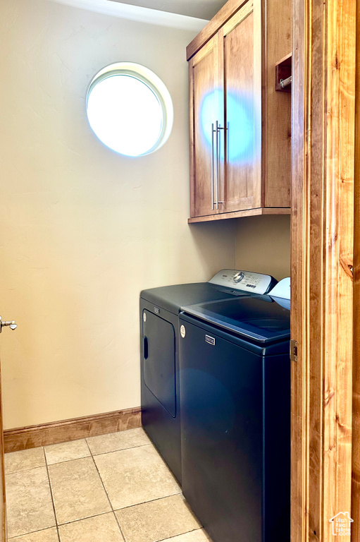 Laundry area featuring cabinet space, washer and dryer, and light tile patterned flooring