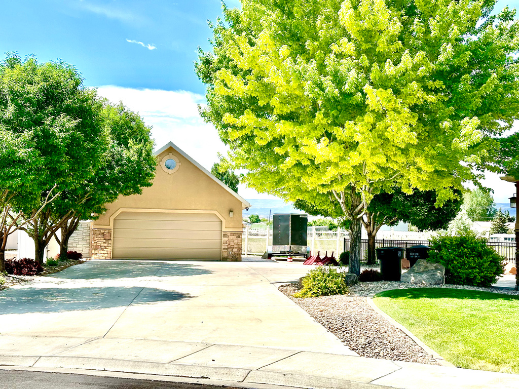 Obstructed view of property with concrete driveway, stucco siding, an attached garage, and stone siding