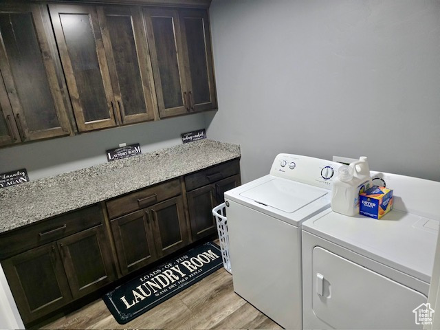 Laundry room with cabinet space, independent washer and dryer, and light wood finished floors