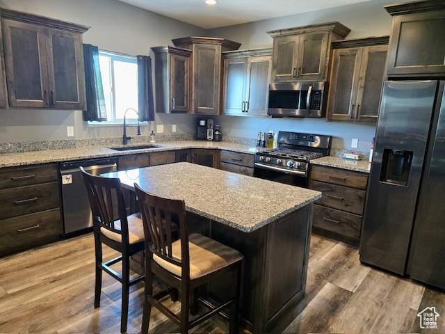 Kitchen featuring stainless steel appliances, recessed lighting, dark brown cabinets, a breakfast bar area, and a center island