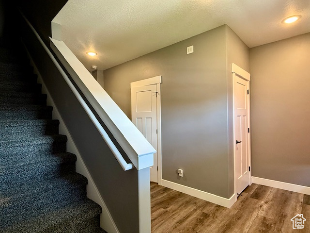 Staircase with wood finished floors and recessed lighting