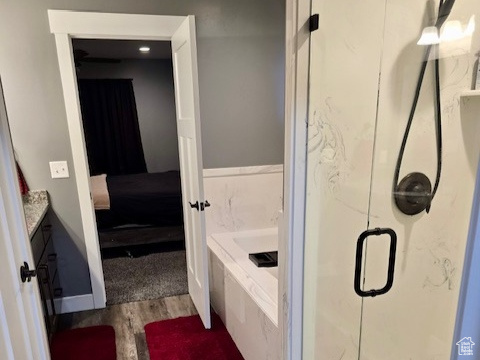 Full bathroom with wood finished floors, a garden tub, a shower stall, ensuite bathroom, and vanity