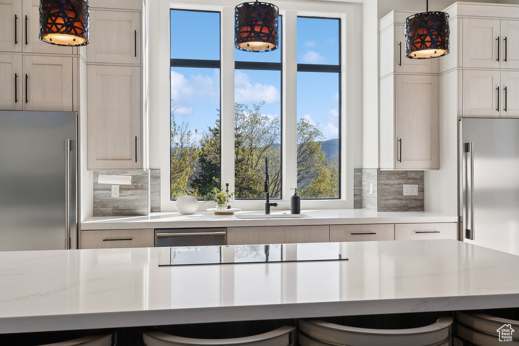 Kitchen with high quality fridge, built in refrigerator, backsplash, and hanging light fixtures