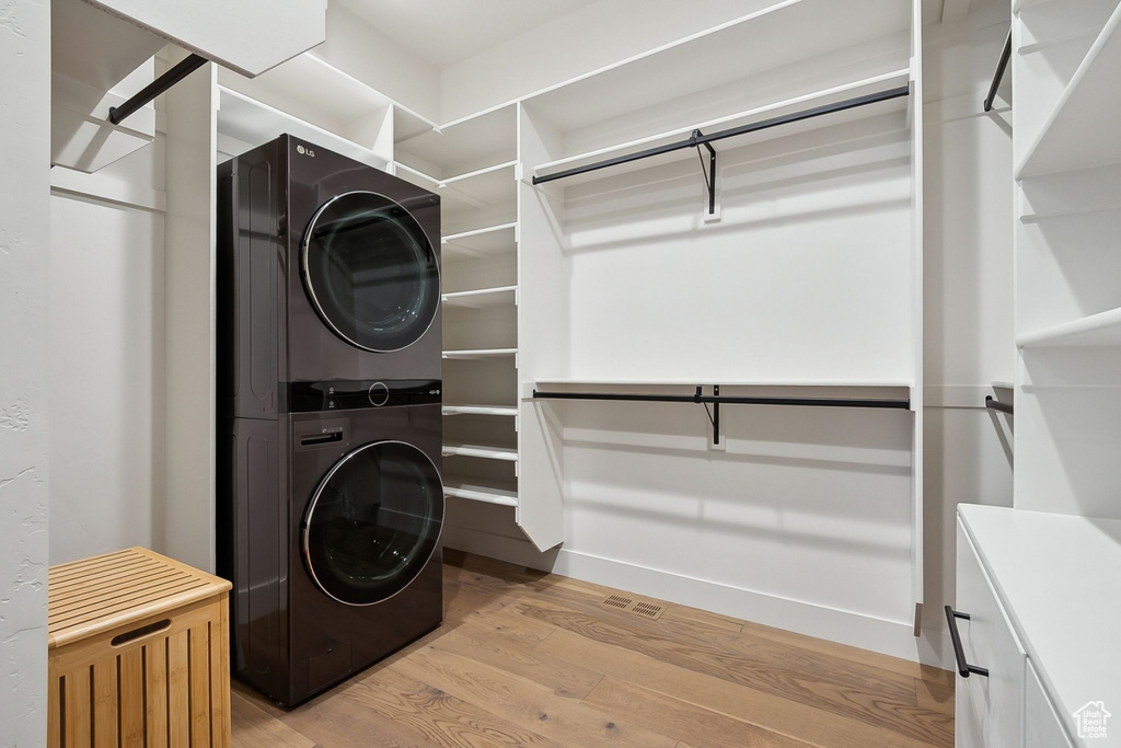 Laundry area featuring stacked washer / dryer and light wood-type flooring
