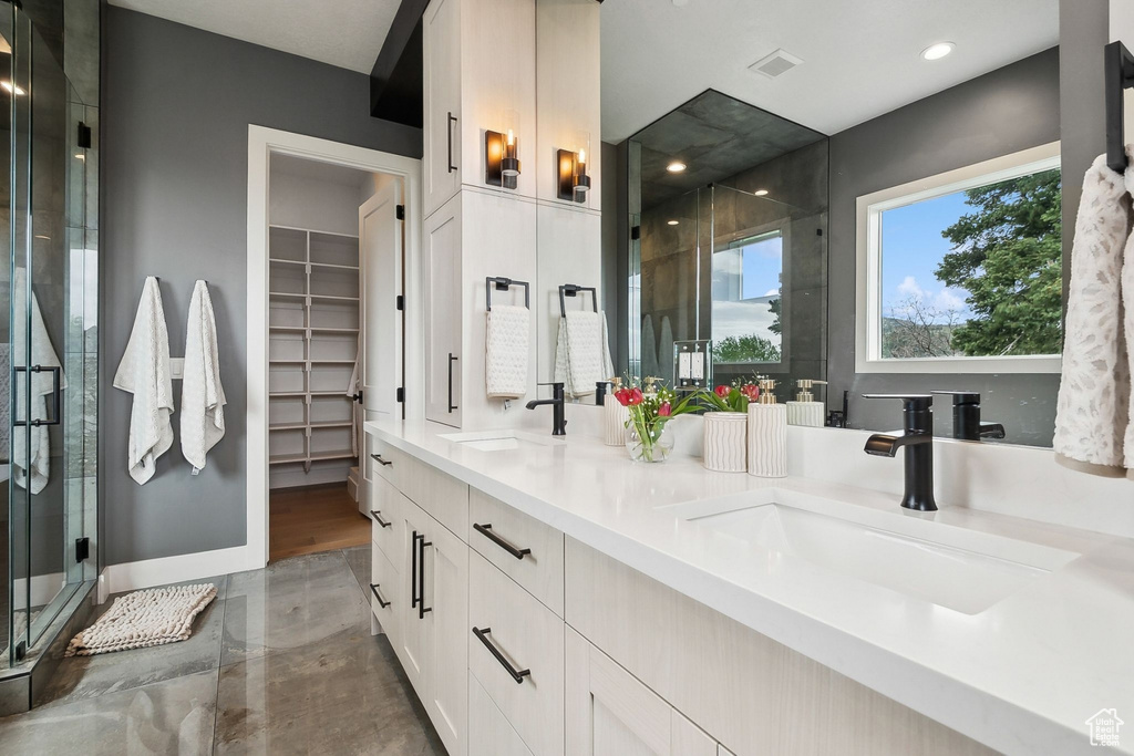 Bathroom featuring a stall shower, double vanity, recessed lighting, and a walk in closet