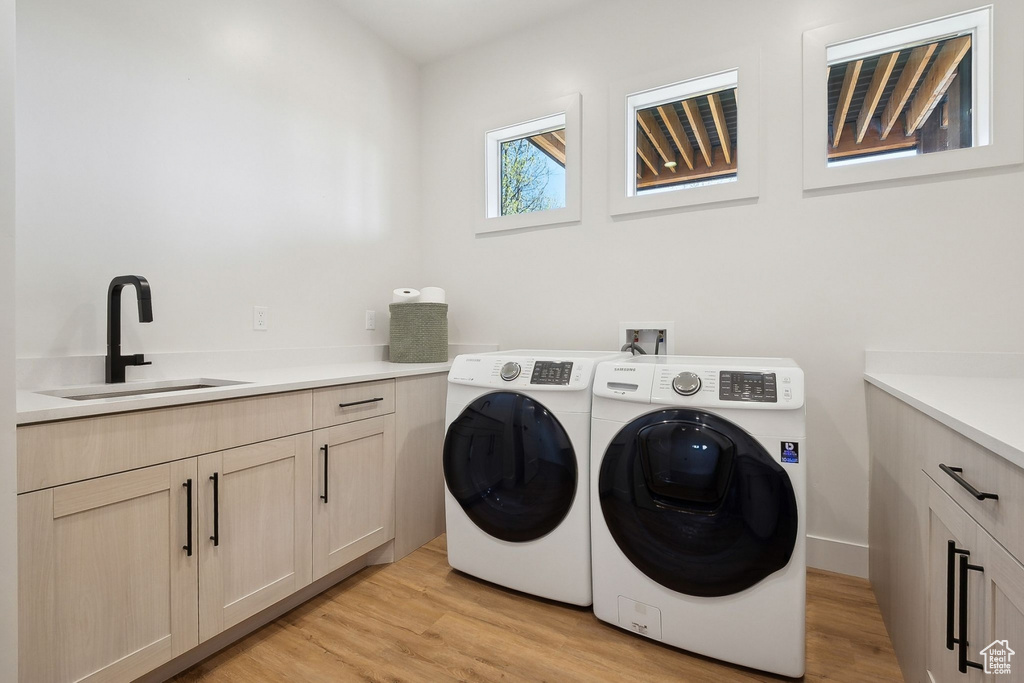 Laundry area with washer and dryer, light wood-type flooring, and cabinet space