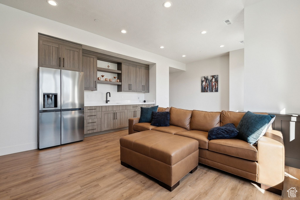 Living room featuring bar with sink, light wood-type flooring, and recessed lighting