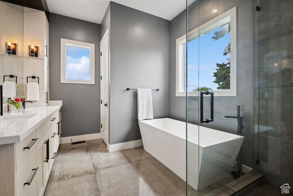 Full bath with double vanity, a freestanding tub, and a shower with shower door