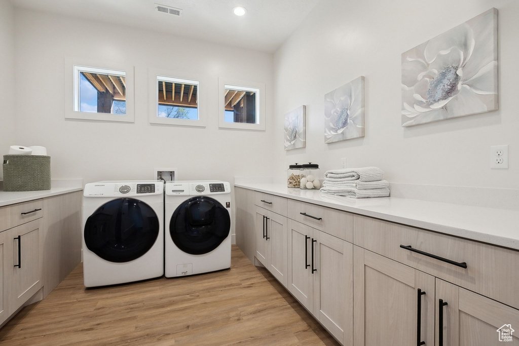 Laundry room featuring washing machine and clothes dryer, cabinet space, light wood-style floors, and recessed lighting