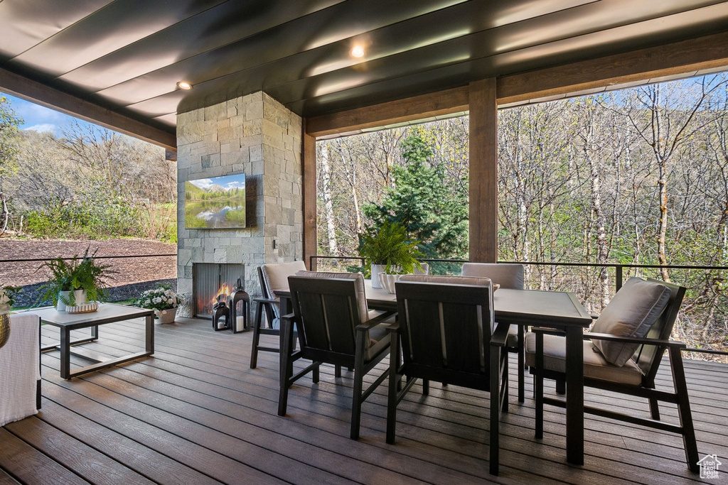 Wooden deck with an outdoor stone fireplace and outdoor dining area