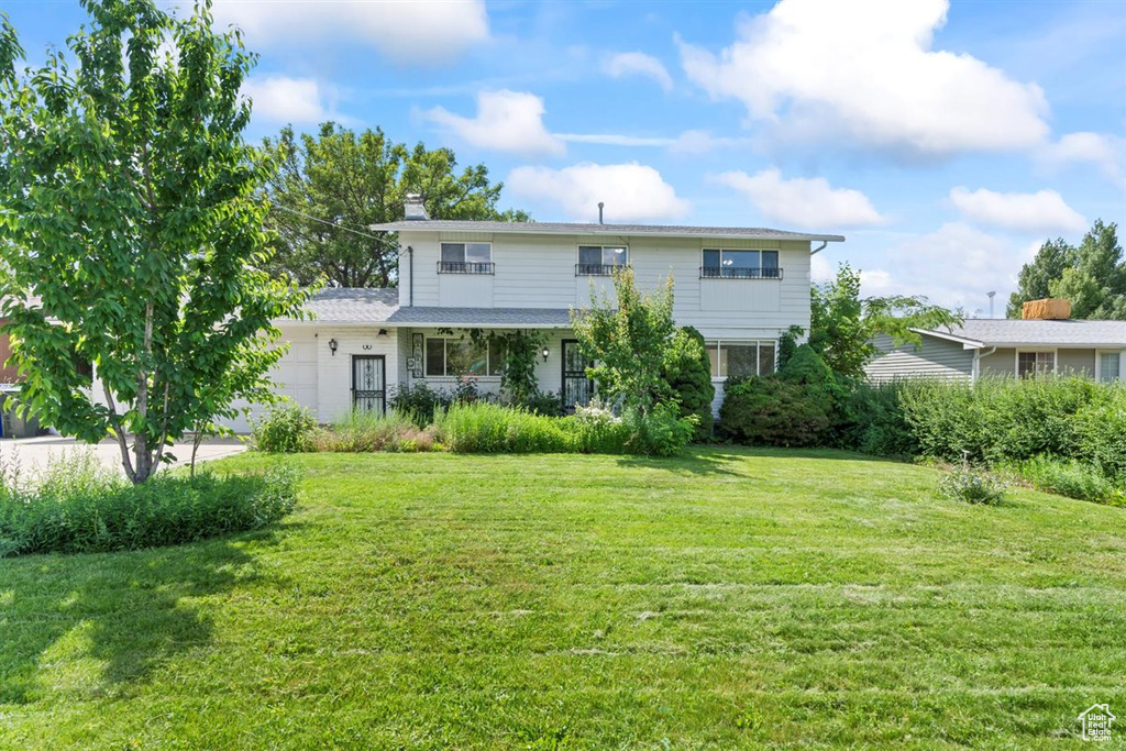Back of property featuring a lawn, an attached garage, and a chimney