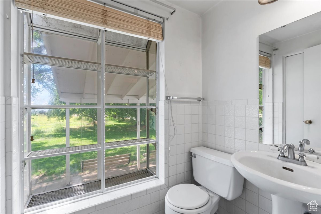 Half bath with tile walls and a wainscoted wall