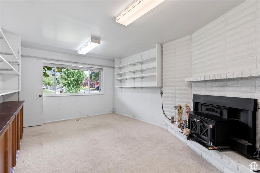 Unfurnished living room with a wood stove and light carpet