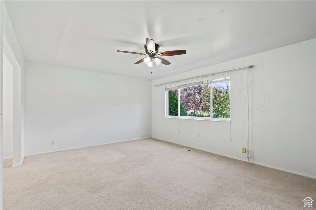 Empty room featuring a ceiling fan and carpet floors