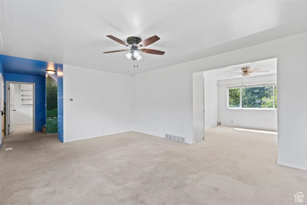 Unfurnished room featuring a ceiling fan and carpet