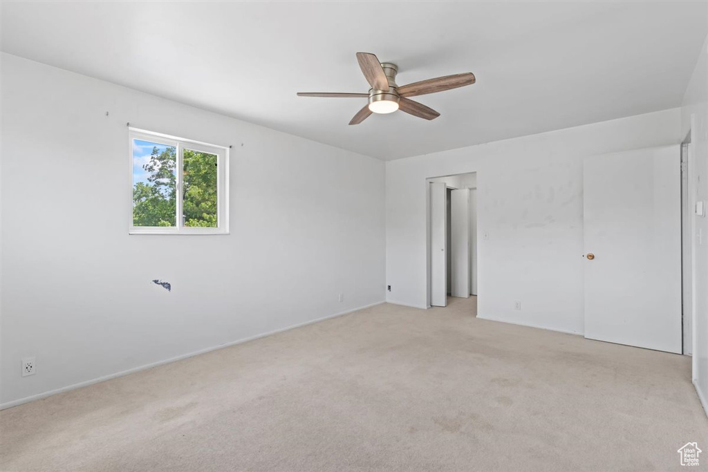 Unfurnished bedroom with light colored carpet and a ceiling fan