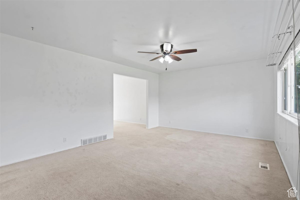 Empty room featuring ceiling fan and light carpet