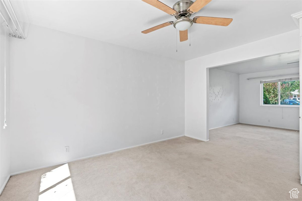 Unfurnished room with light colored carpet and ceiling fan