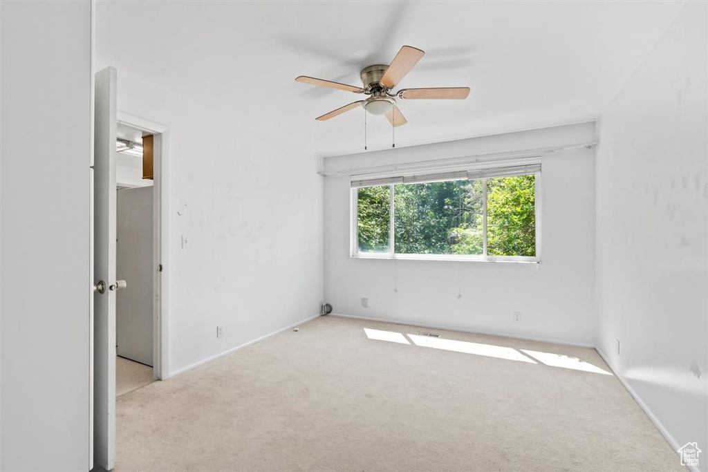 Empty room featuring carpet flooring and a ceiling fan