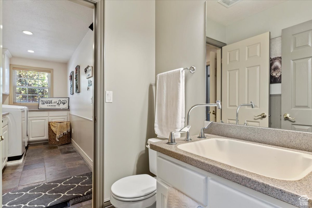 Bathroom with vanity, stone finish floors, recessed lighting, and washer / dryer