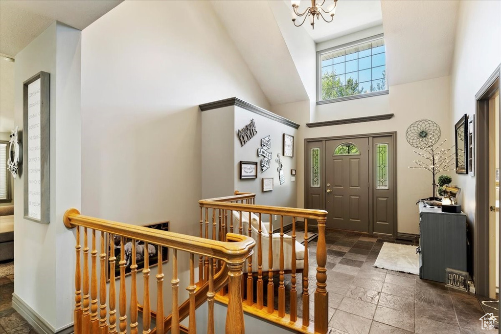Entryway featuring stone tile floors, a chandelier, and high vaulted ceiling