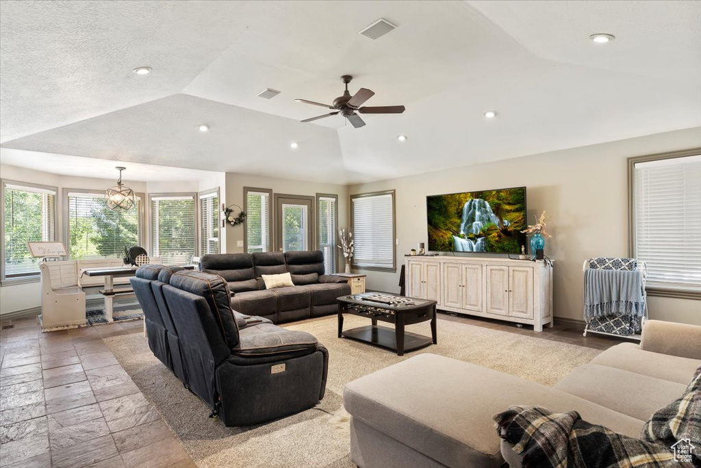 Living room featuring lofted ceiling, recessed lighting, a ceiling fan, and stone tile floors