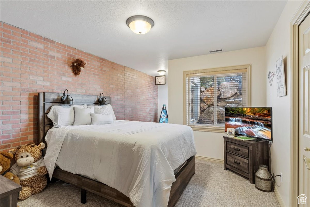 Bedroom with brick wall and light colored carpet