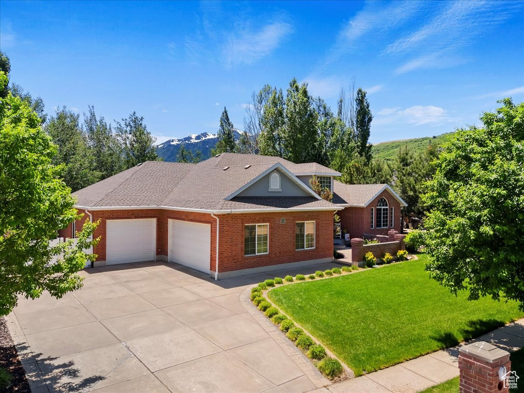 View of front of house with an attached garage, a front lawn, brick siding, concrete driveway, and roof with shingles