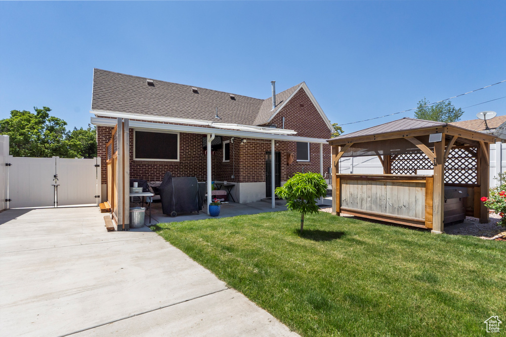 Back of property featuring a gazebo, a gate, brick siding, a patio area, and a shingled roof